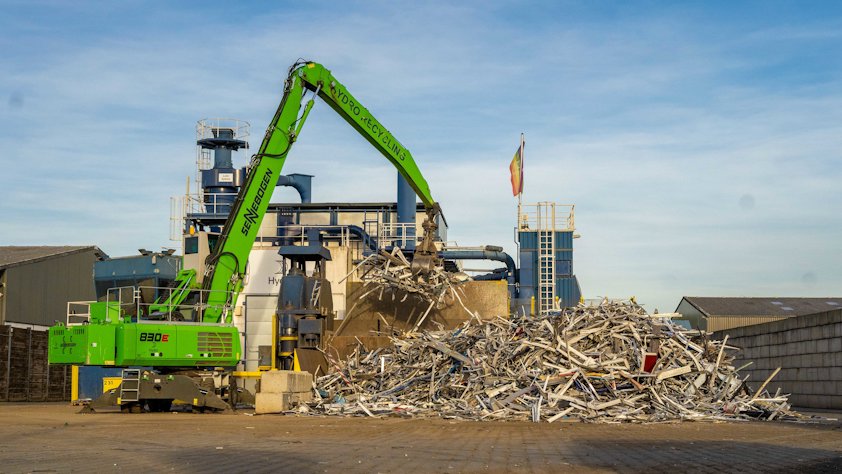 A crane lifting a pile of aluminium scrap
