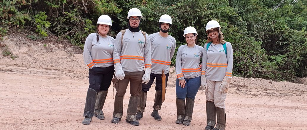 a group of people wearing hardhats and standing on a dirt road