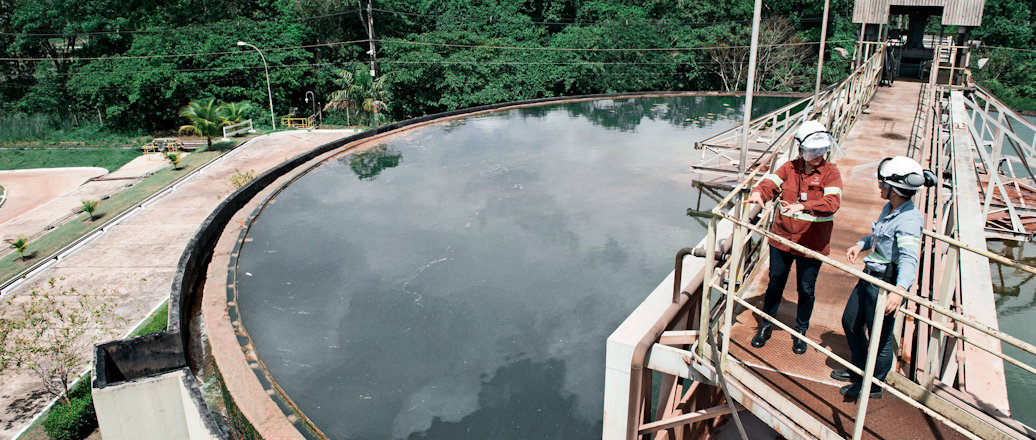 Two people talking on a metal bridge over a water tank