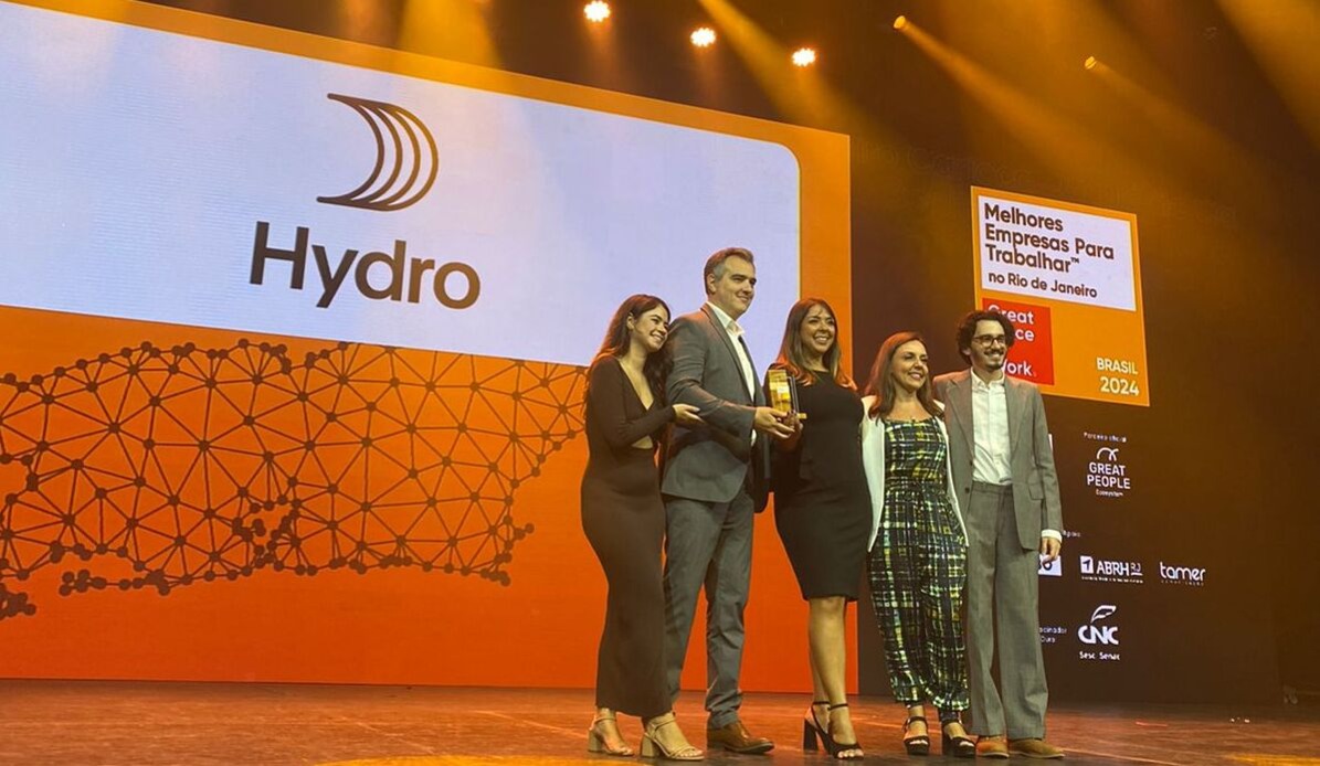 a group of people standing on a stage with a sign behind them