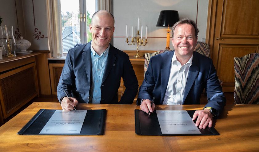 a couple of men sitting at a table with a book and a pen