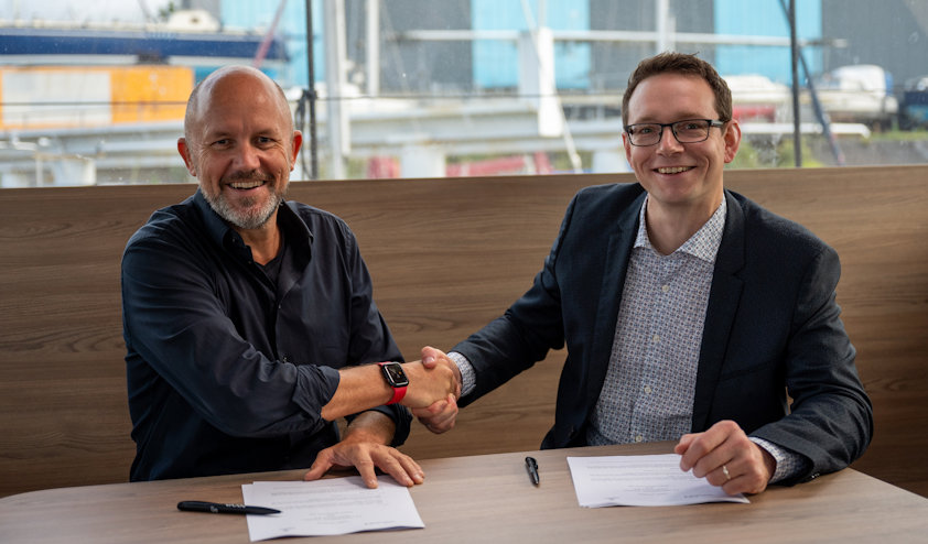 a couple of men sitting at a table with papers and pens