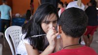 Volunteer doing face painting on child