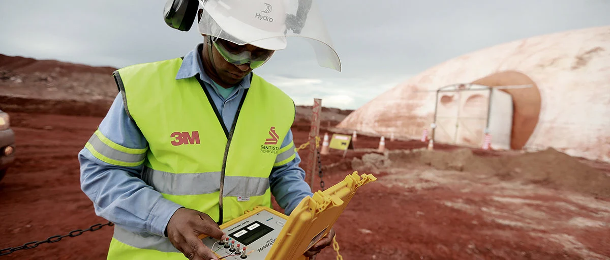 a man in a safety vest and helmet using a device