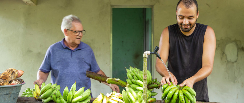 a couple of men stand near each other holding bananas
