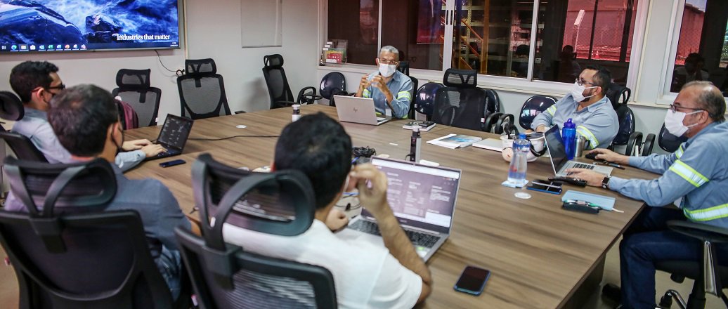 a group of people sitting around a table with laptops