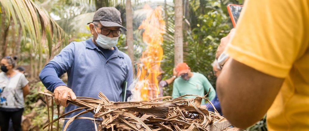 a person wearing a mask and holding a stick with fire in the background