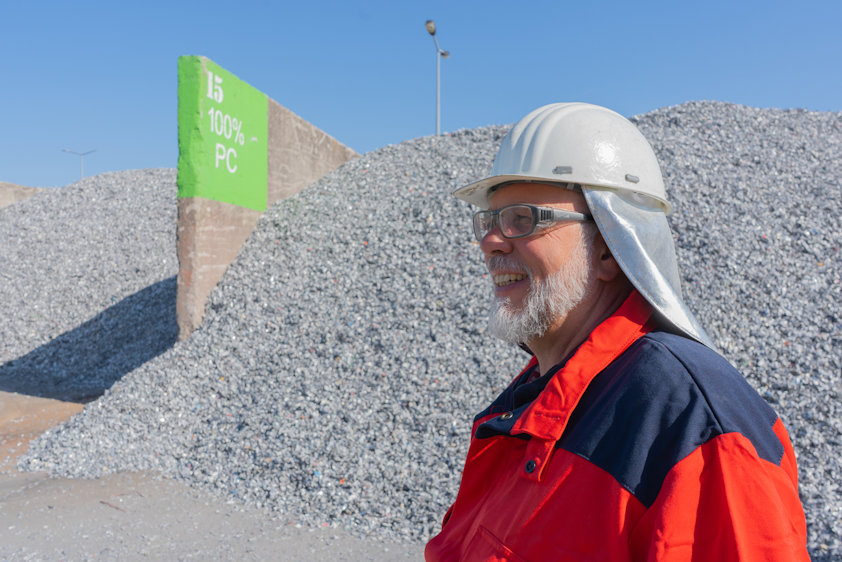 a man wearing a hard hat and glasses standing in front of a rock